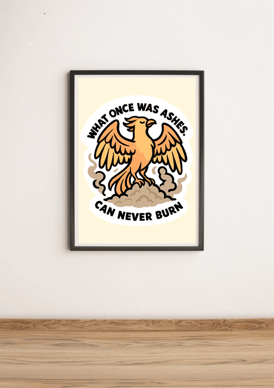Framed wall art print featuring a bold orange phoenix rising from ashes, with the quote "What once was ashes can never burn" in strong black lettering, set against a light neutral background.