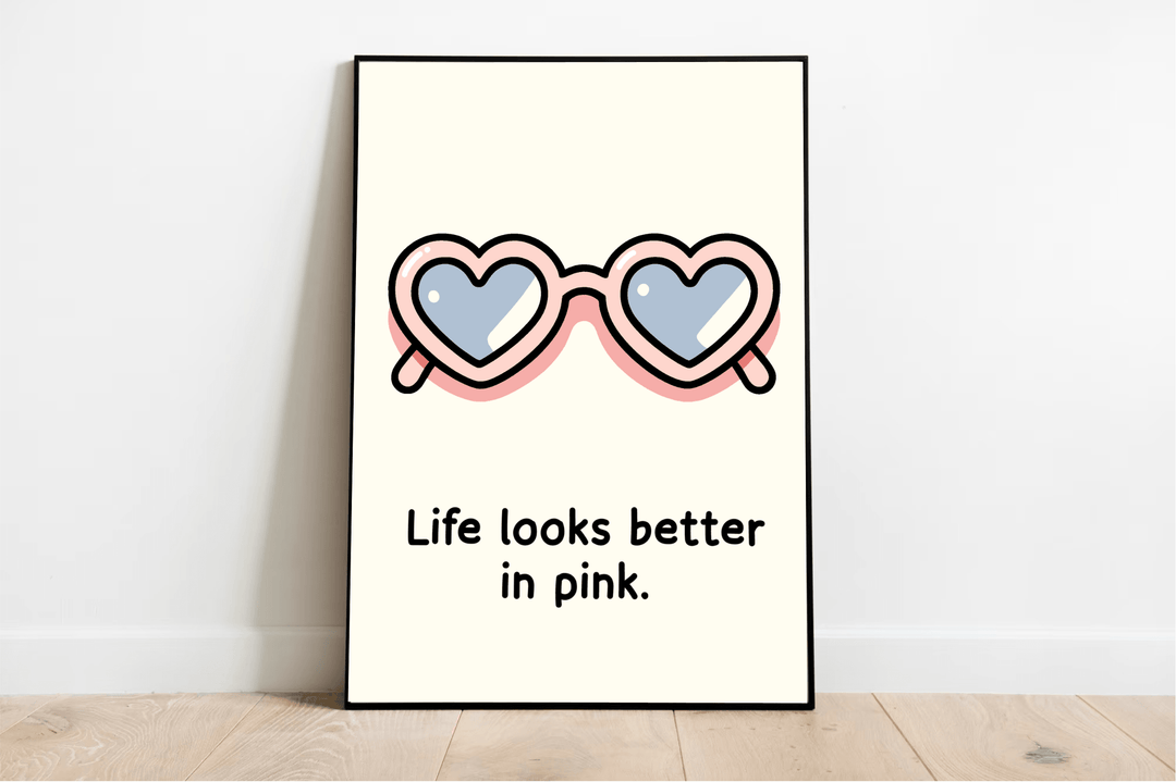 Introducing the "Life Looks Better in Pink Print"! This delightful illustration showcases heart-shaped sunglasses with adorable pink frames and cool, reflective blue lenses, capturing a whimsical sense of positivity. Beneath the charming artwork, bold black lettering proclaims, "Life looks better in pink." Perfectly placed on a light wooden floor against a crisp white wall, this eye-catching pink art print is sure to add a splash of joy to any space!