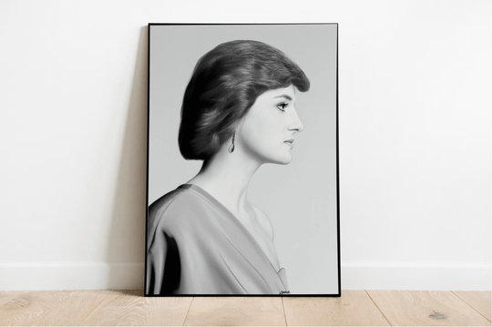 Introducing "Eternal Grace - Handcrafted Princess Diana Print," a stunning black and white framed portrait that radiates timeless elegance. This captivating piece showcases a woman in profile, set beautifully on a wooden floor against a pristine white wall. With short, wavy locks and an elegant off-the-shoulder dress reminiscent of Princess Diana's iconic style, this print truly embodies the essence of royalty. A delicate dangling earring adds just the right touch of grace, making this subtly tilted image p