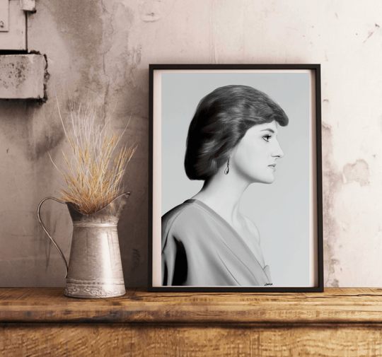 Introducing "Eternal Grace - Handcrafted Princess Diana Print," a stunning black and white framed portrait that radiates timeless elegance. This captivating piece showcases a woman in profile, set beautifully on a wooden floor against a pristine white wall. With short, wavy locks and an elegant off-the-shoulder dress reminiscent of Princess Diana's iconic style, this print truly embodies the essence of royalty. A delicate dangling earring adds just the right touch of grace, making this subtly tilted image p