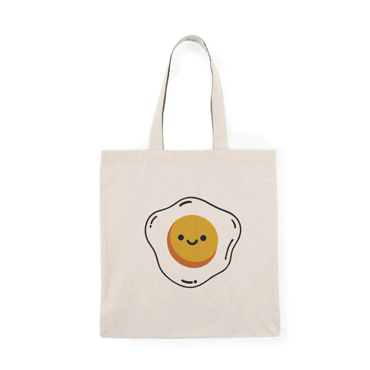 A reusable tote bag featuring a cute fried egg illustration with a smiling face on natural recycled cotton. Optionally includes "You're a Good Egg" text.