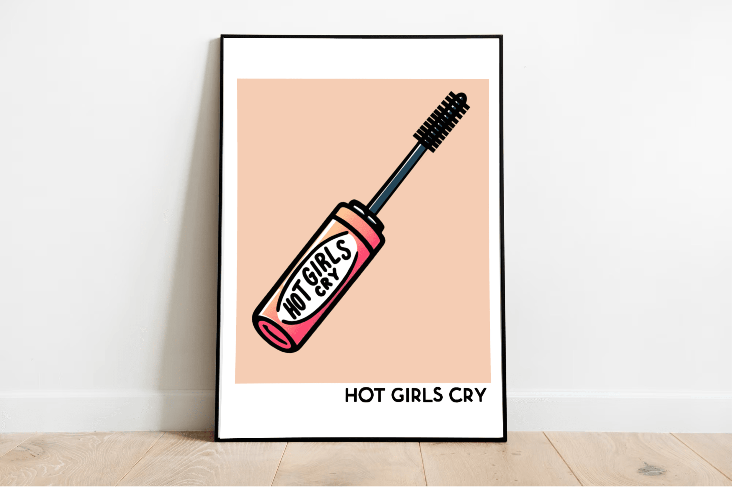 Check out the "Hot Girls Cry Print," showcasing a fun illustration of a pink mascara tube with the bold phrase "HOT GIRLS CRY" on its side. This piece perfectly balances empowering strength and genuine vulnerability. The print pops with a peach background and striking black letters that really drive the message home. It's elegantly displayed leaning against a white wall on a light wooden floor, making it an eye-catching addition to any room.