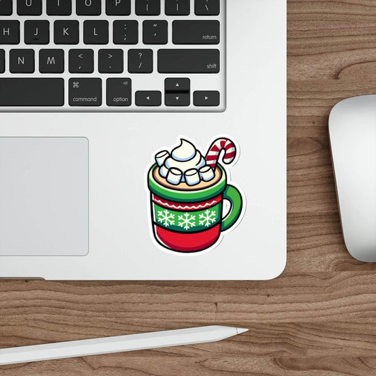 A festive sticker featuring a cozy mug of hot chocolate with whipped cream, marshmallows, and a candy cane, designed in vibrant holiday colors. The sticker is placed on a sleek laptop, showcasing its versatility and cheerful design.
