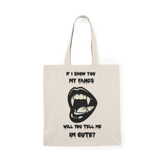A natural canvas tote bag showcasing a cheeky design with a cartoonish mouth displaying fangs and the text 'If I show you my fangs, will you tell me I'm cute?' The playful combination of humor and confidence makes this tote a great conversation starter."