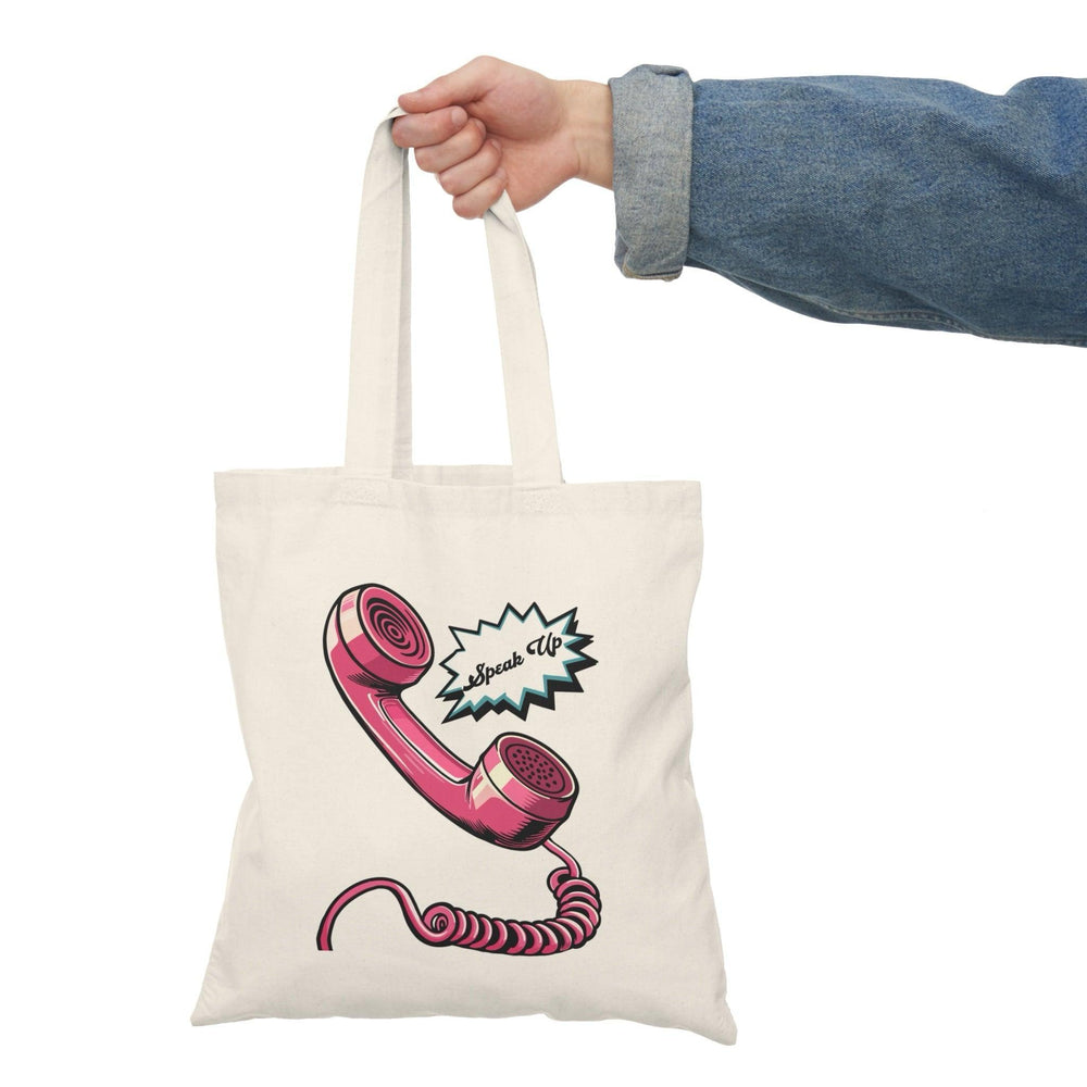 A cream-colored tote bag featuring a graphic of a vintage telephone and the text 'Speak Up.' The retro design encourages communication and expression, making it a meaningful accessory for those who value conversation.