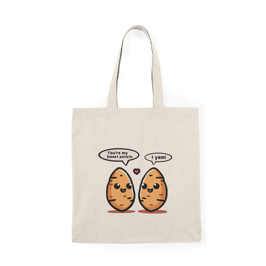 A cream-colored tote bag featuring a whimsical illustration of two sweet potatoes with smiling faces. The cute design adds a playful touch to this bag, appealing to food enthusiasts and anyone who enjoys a bit of fun in their accessories