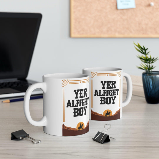 Playful ceramic mug featuring the phrase 'Yer Alright Boy' against a desert scene. A fun gift for friends or family, perfect for morning coffee or tea - Baby Keo