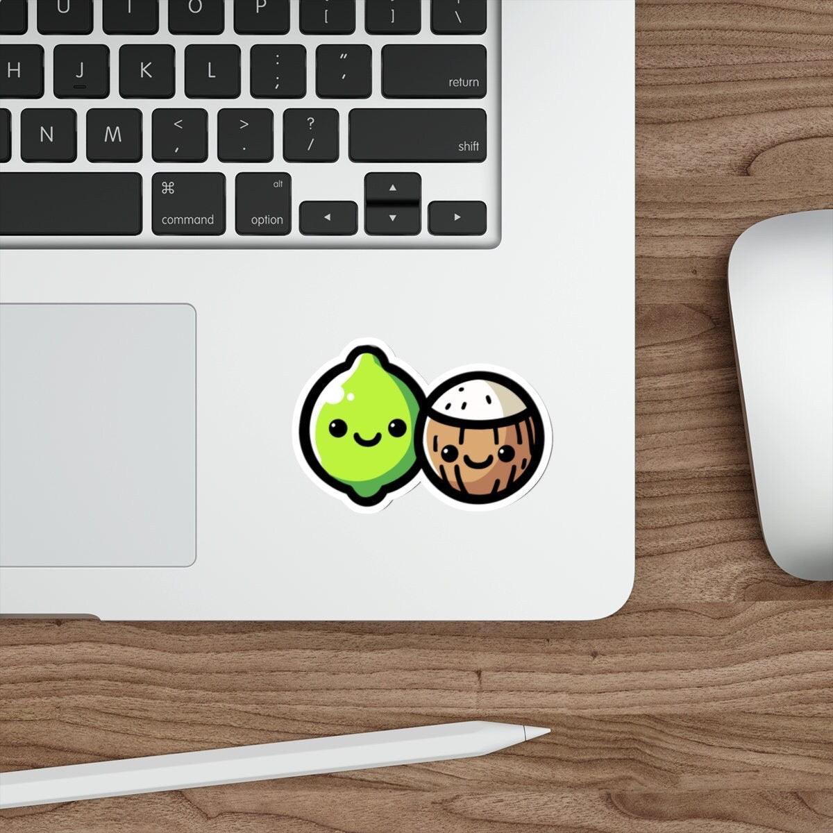 A sticker with a cartoon lime and coconut design placed on a laptop.