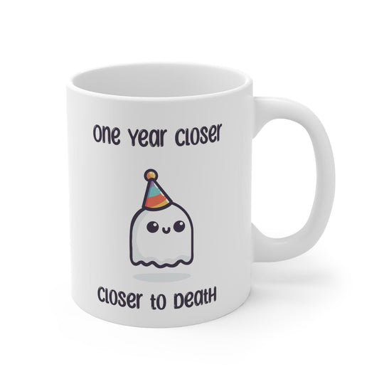 White ceramic mug featuring a ghost illustration and the darkly humorous text 'One Year Closer to Death,' perfect for those who enjoy a bit of morbid humor