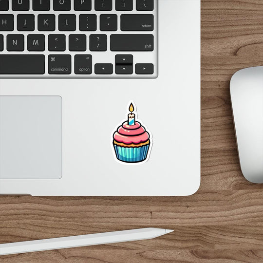 A sticker depicting a cartoon cupcake with a candle on top, placed on a laptop next to a mouse, representing the product&