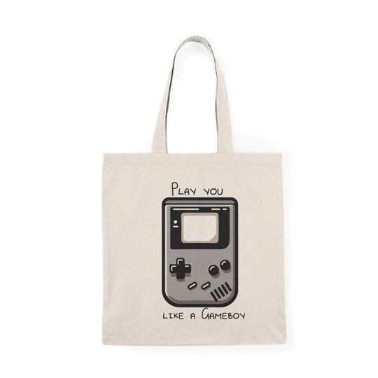 A cream tote bag featuring a retro Gameboy graphic with the phrase 'Play you like a Gameboy' in a fun font. This nostalgic design appeals to gaming enthusiasts and adds a playful touch to everyday accessories.