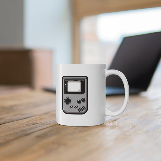 White ceramic mug featuring a nostalgic Gameboy design in gray and black, perfect for retro gaming enthusiasts.