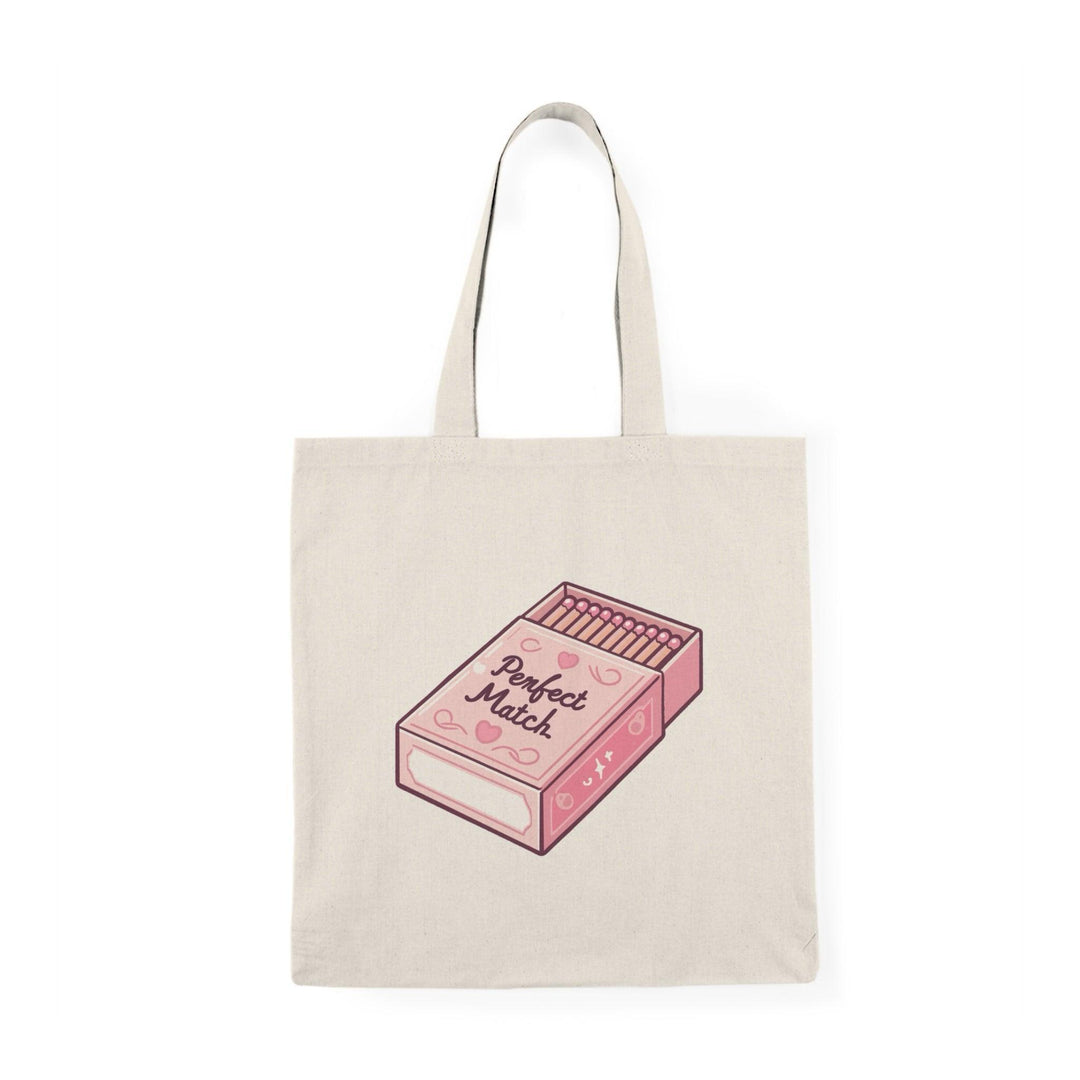 A cream tote bag featuring an artistic illustration of a matchbox with the phrase 'Perfect Match' written in a stylish font. The creative design gives a nod to love and connection, making it an ideal gift for couples or those who appreciate clever graphics