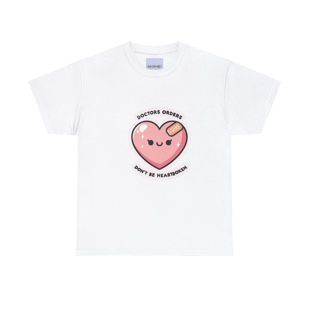 White T-shirt featuring a cute pink heart character with a bandage, accompanied by the phrase 'Doctor's Orders: Don't Be Heartbroken.' A light-hearted design offering an encouraging message of emotional healing.
