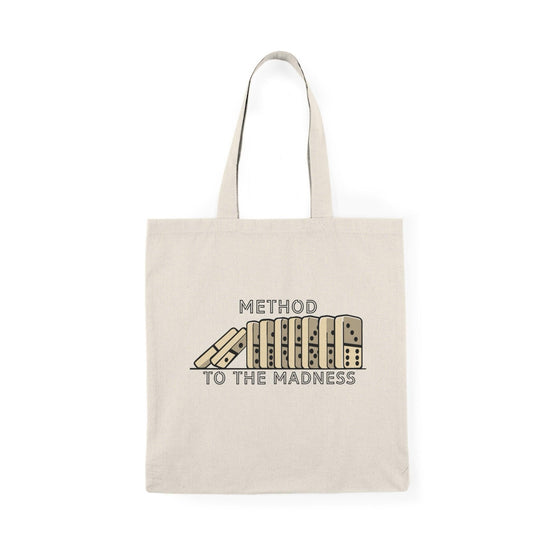 A cream-colored tote bag featuring a quirky design with the phrase 'Method to the Madness' accompanied by a whimsical illustration of a pencil and a notepad. The playful font and graphic emphasize a humorous take on creativity and the chaotic process of brainstorming