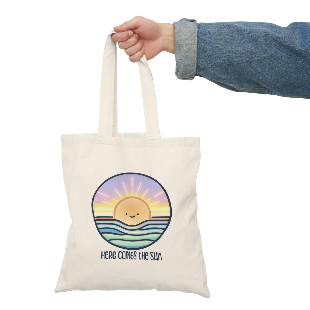 Tote bag featuring a cheerful illustration of a bright sun with a smiling face, surrounded by vibrant rays and colorful elements. The uplifting design embodies positivity and warmth, making it a perfect accessory for sunny days or adding a bright touch to your everyday carry.
