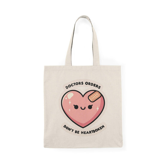 Tote bag featuring a playful and humorous design with the phrase 'Doctor's Orders: Don't Be Heartbroken.' The vibrant typography and fun graphics create a lighthearted accessory, perfect for adding a touch of humor and positivity to your everyday style while conveying a message of resilience."