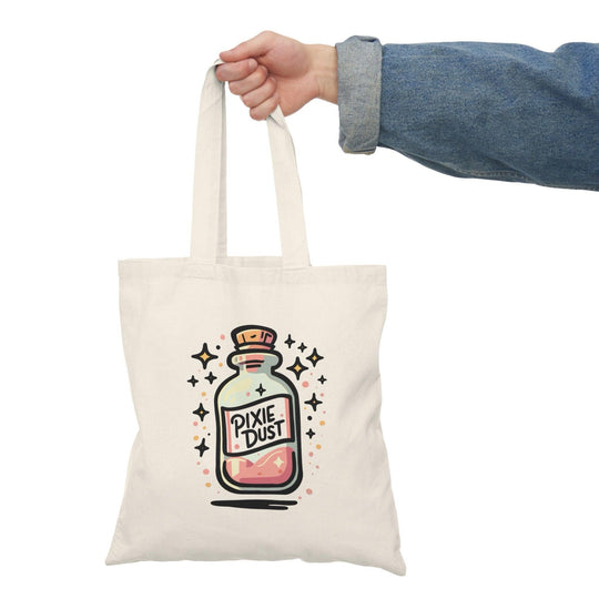 A natural canvas tote bag showcasing a whimsical design of a potion bottle labeled 'Pixie Dust,' surrounded by sparkling stars. The enchanting graphic captures the essence of magic and fantasy, perfect for those who love all things mystical