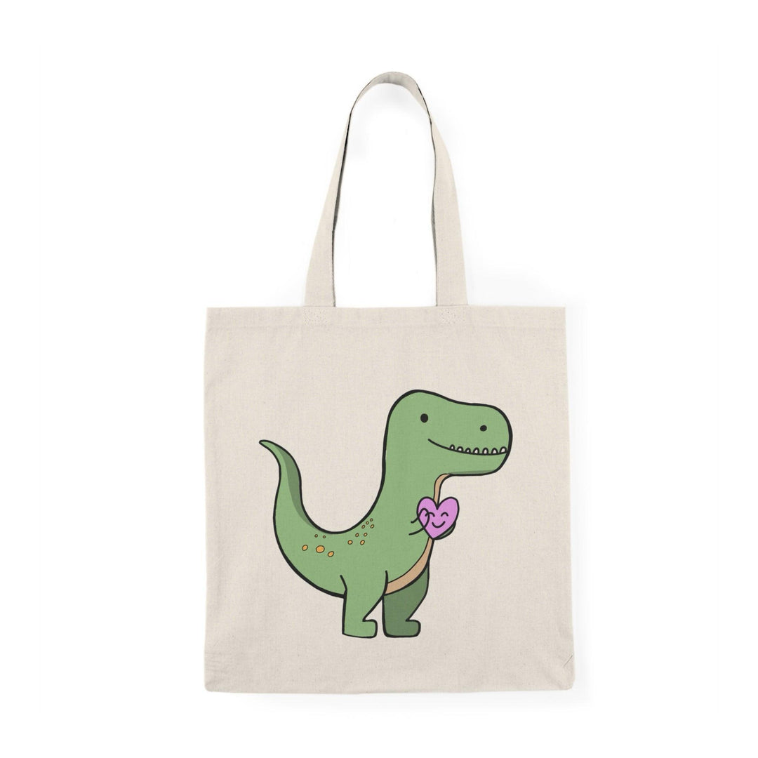 A natural canvas tote bag showcasing a charming graphic of a T-rex holding a pink heart. The cute and humorous design combines love and prehistoric fun, making it an ideal accessory for dinosaur lovers and those with a quirky sense of humor.