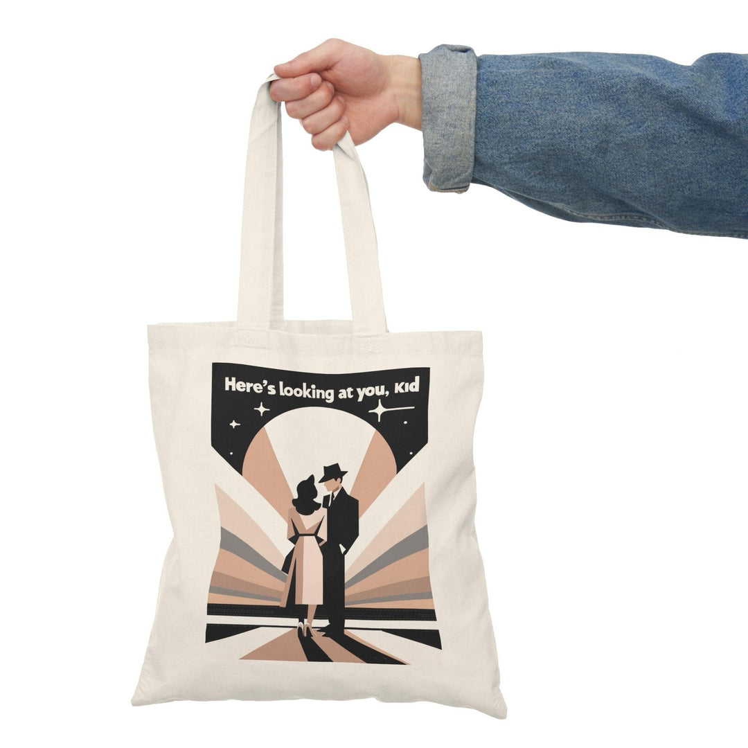 Stylish canvas tote bag featuring a vintage-inspired design with a figure in a suit and the quote 'Here’s Looking at You Kid' in black and white. A perfect tote for movie lovers or vintage enthusiasts - Baby Keo