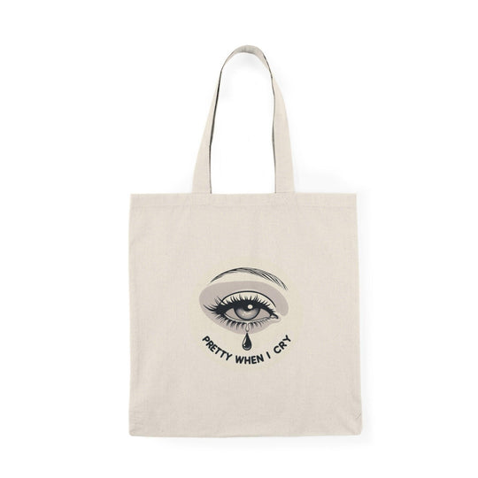 A natural canvas tote bag showcasing an artistic graphic of a teardrop with the phrase 'Pretty When I Cry.' The thoughtful design combines emotion with beauty, appealing to those who embrace vulnerability and self-expression