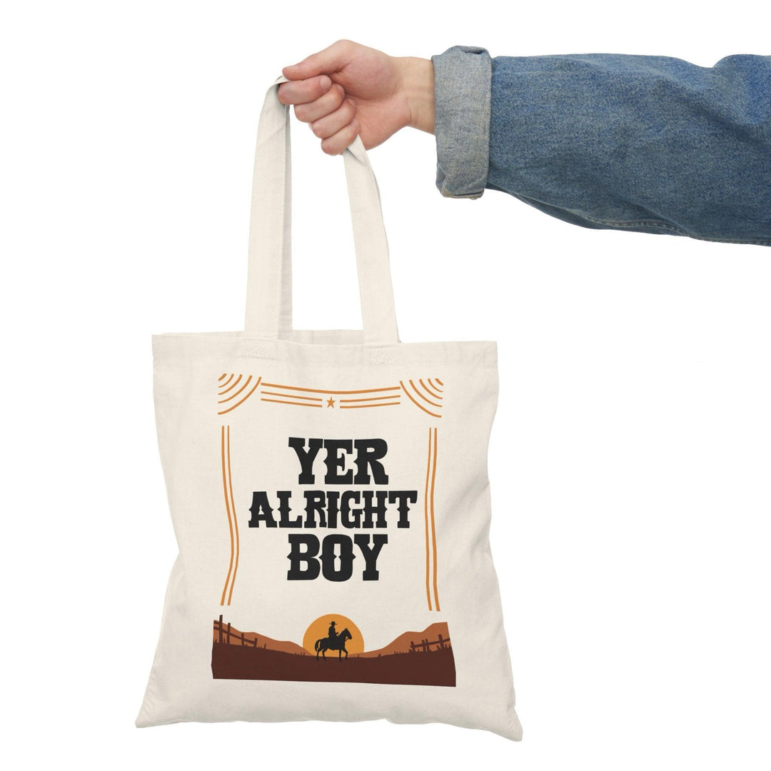 A natural tote bag with bold typography stating 'Yer Alright Boy,' accompanied by a graphic of a landscape. This fun design adds a lighthearted, friendly touch, making it perfect for those with a charming sense of humor