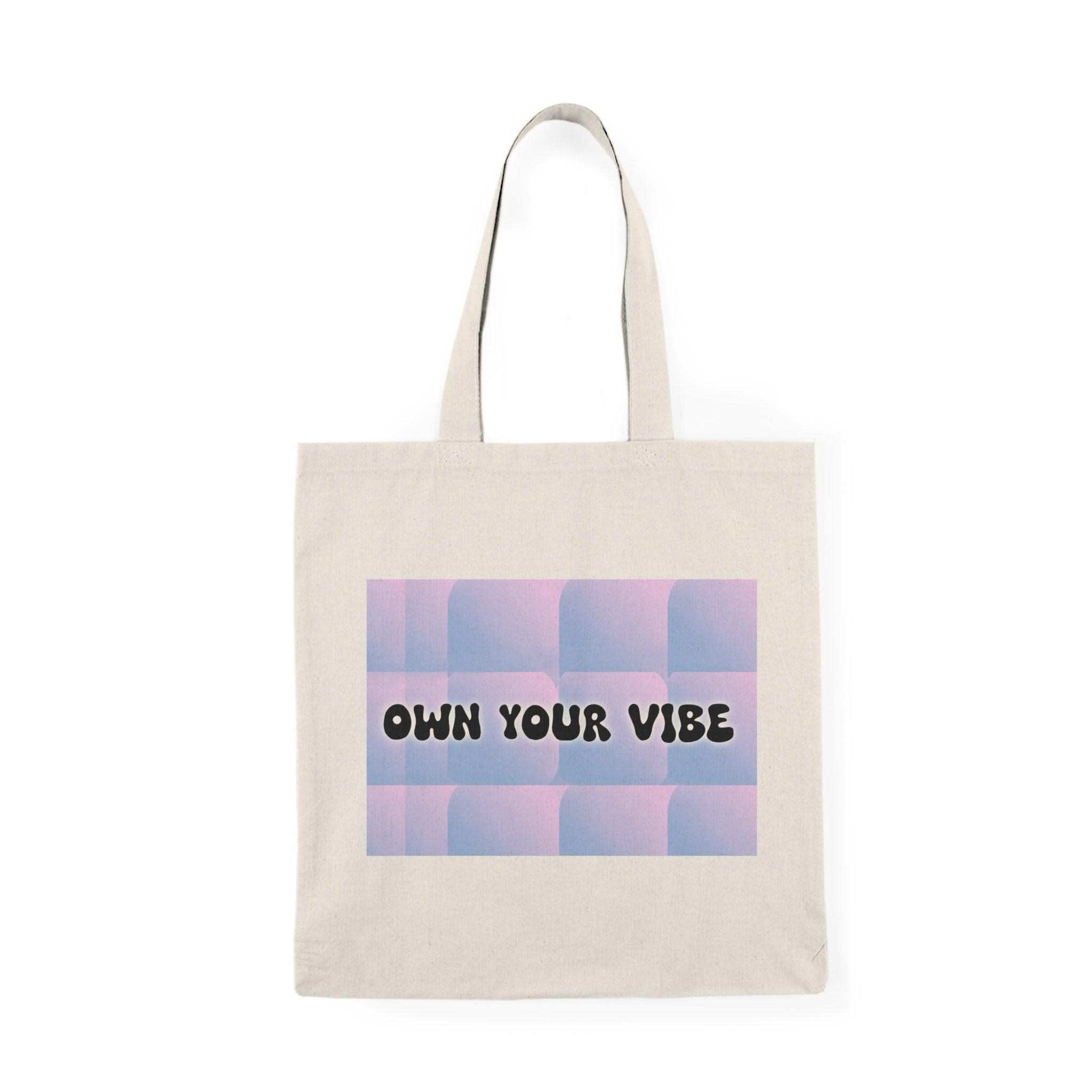 A natural tote bag showcasing the text 'Own Your Vibe' in a modern, stylish font against a gradient background. The design encourages positivity and self-expression, making it an uplifting addition to any outfit