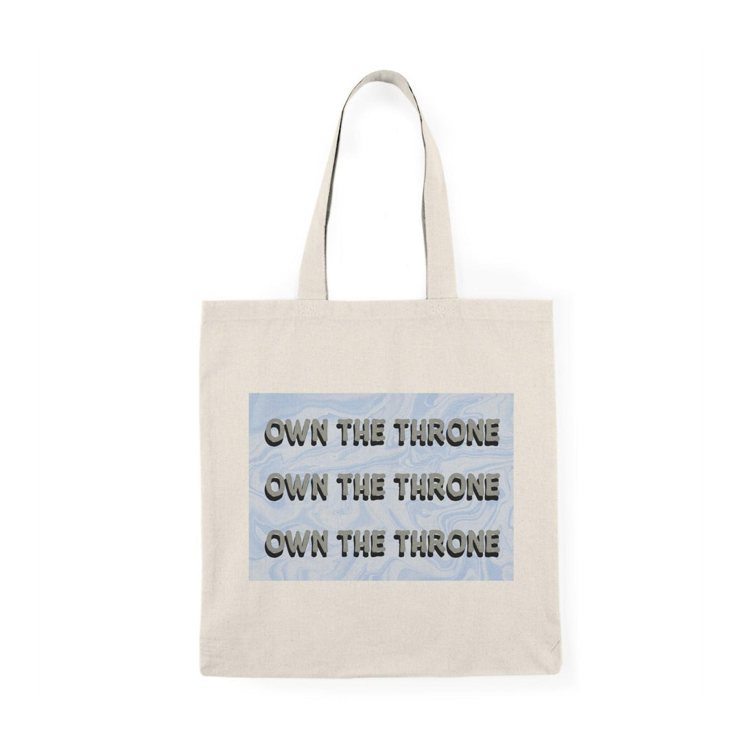 A cream tote bag featuring the phrase 'Own The Throne' repeated in a stylish and colorful font. The vibrant colors and eye-catching design inspire confidence and empowerment, making it a great accessory for those who want to make a statement