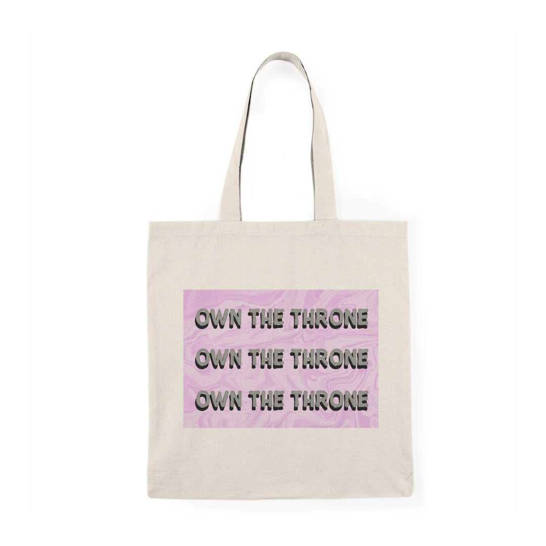A cream tote bag featuring the phrase 'Own The Throne' repeated in a stylish and colorful font. The vibrant colors and eye-catching design inspire confidence and empowerment, making it a great accessory for those who want to make a statement