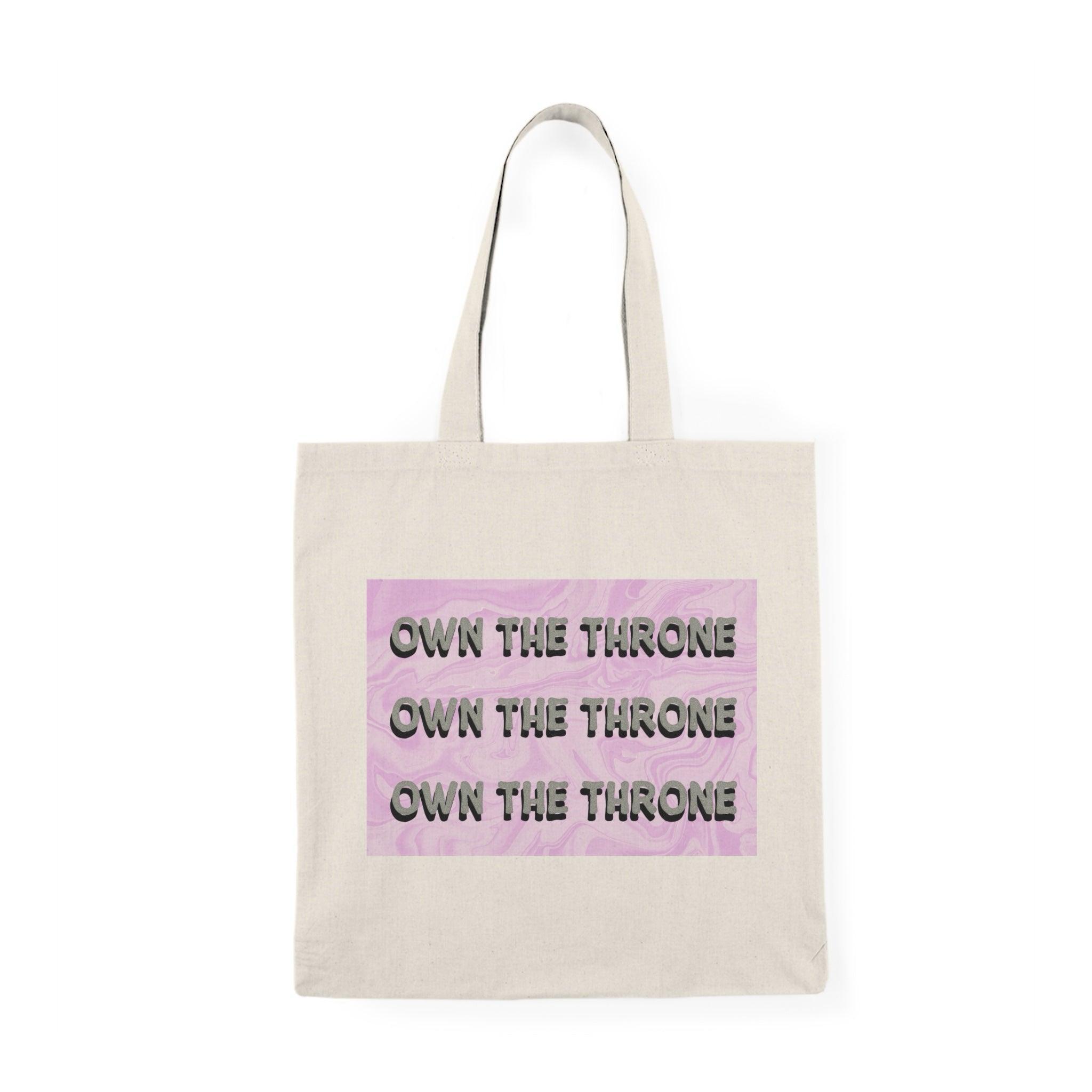 A cream tote bag featuring the phrase 'Own The Throne' repeated in a stylish and colorful font. The vibrant colors and eye-catching design inspire confidence and empowerment, making it a great accessory for those who want to make a statement