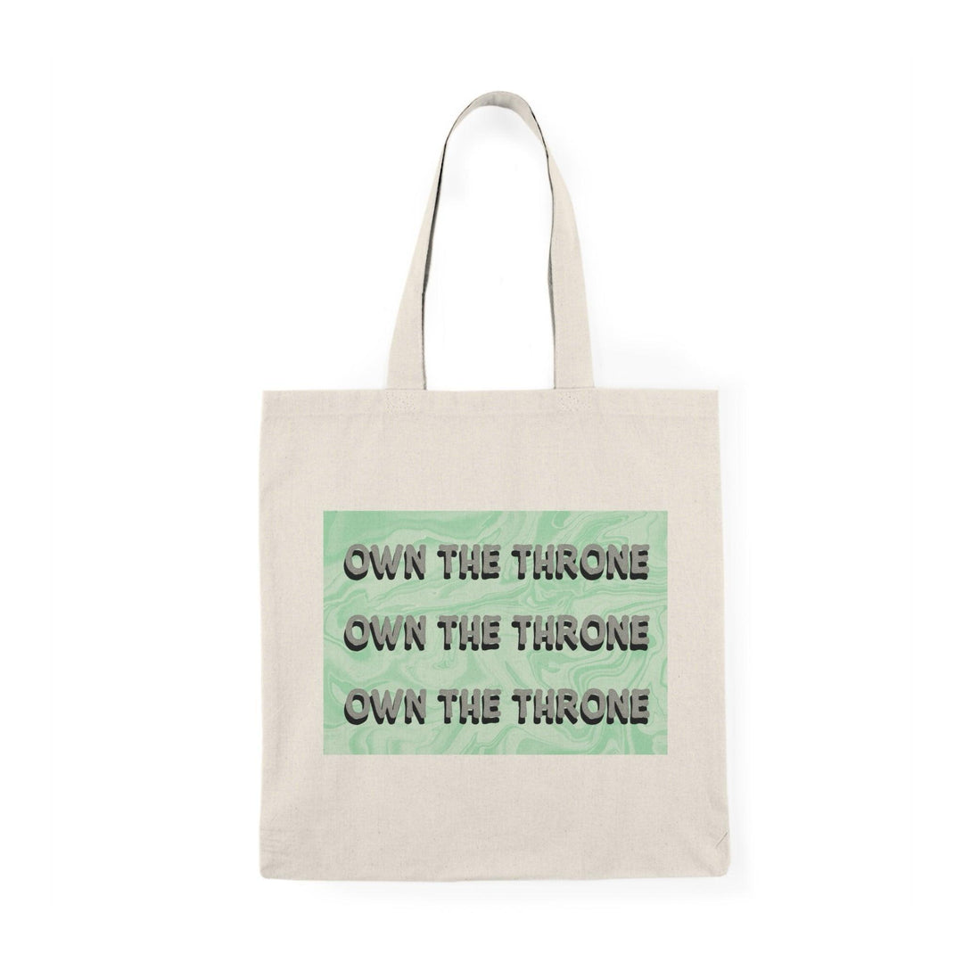 A cream tote bag featuring the phrase 'Own The Throne' repeated in a stylish and colorful font. The vibrant colors and eye-catching design inspire confidence and empowerment, making it a great accessory for those who want to make a statement