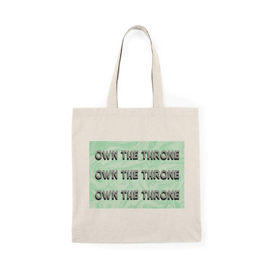 A cream tote bag featuring the phrase 'Own The Throne' repeated in a stylish and colorful font. The vibrant colors and eye-catching design inspire confidence and empowerment, making it a great accessory for those who want to make a statement