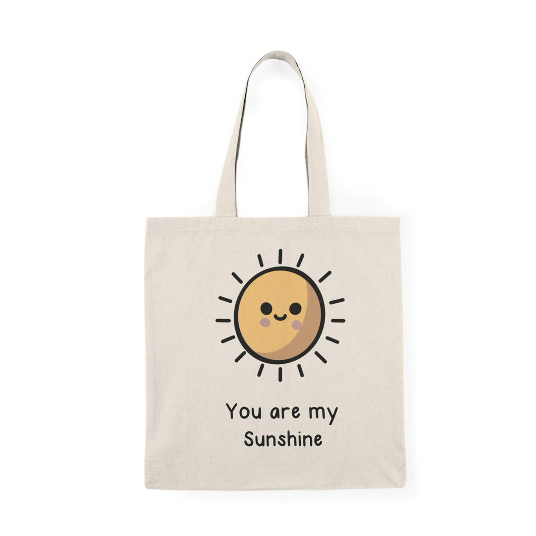A cream-colored tote bag featuring a bright, cheerful sun illustration with the text 'You Are My Sunshine.' The uplifting design evokes feelings of happiness and warmth, making it an ideal gift for loved ones.