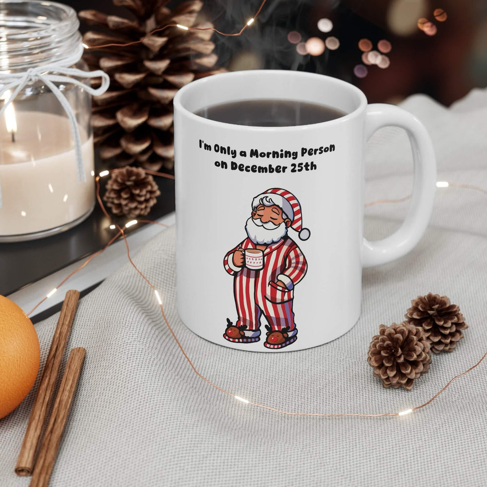 Funny Christmas mug featuring cozy Santa in red-striped pajamas with the phrase 'I'm Only a Morning Person on December 25th.' Perfect for coffee, hot cocoa, or tea during the holiday season