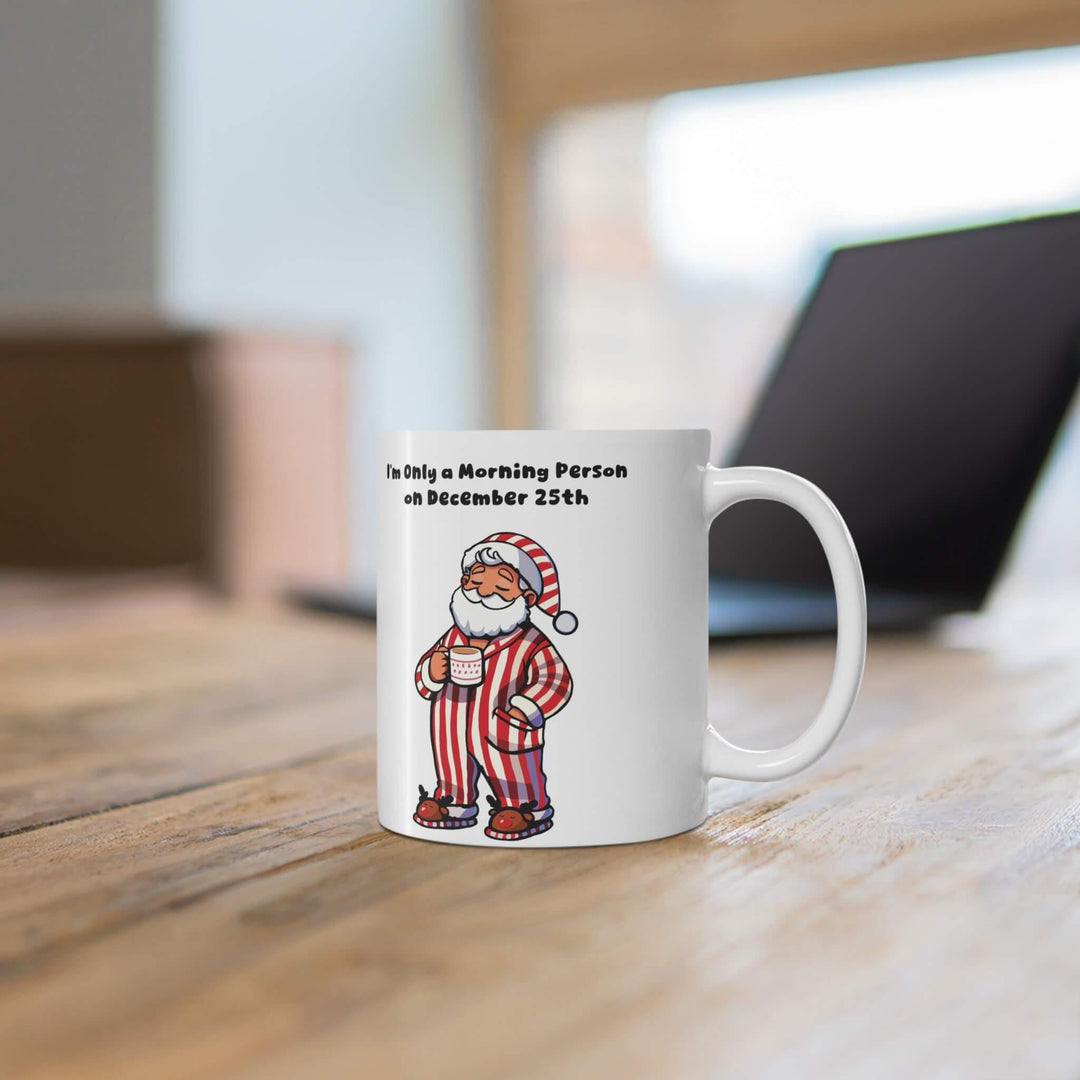 Funny Christmas mug featuring cozy Santa in red-striped pajamas with the phrase 'I'm Only a Morning Person on December 25th.' Perfect for coffee, hot cocoa, or tea during the holiday season