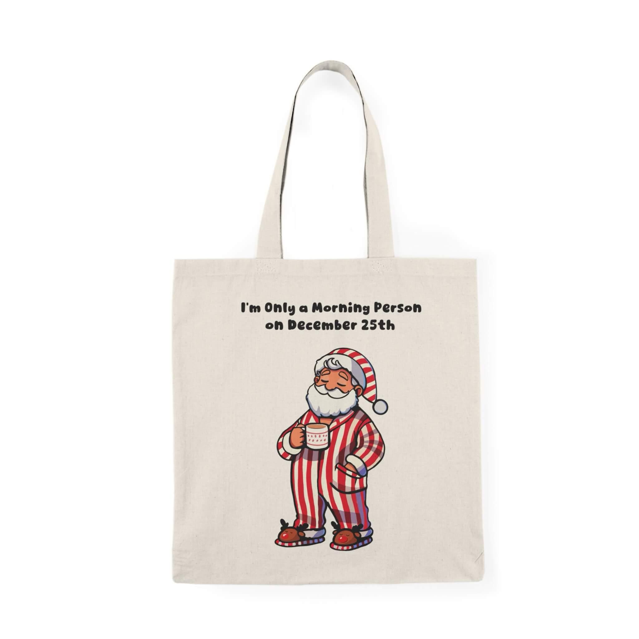 Funny Christmas tote bag with cozy Santa in striped pajamas and the phrase 'I'm Only a Morning Person on December 25th.' Perfect for holiday shopping, made from 100% recycled cotton