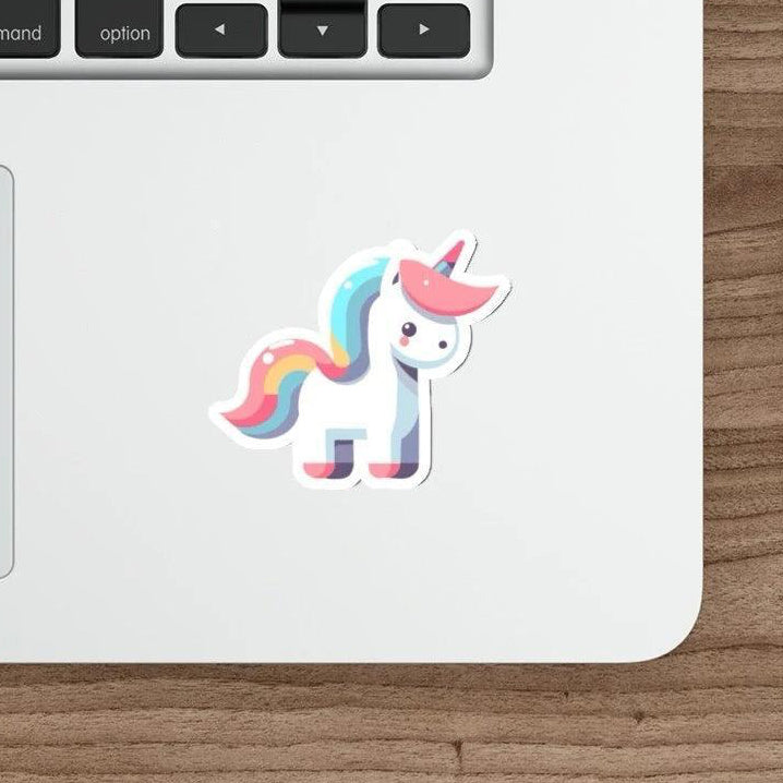 A cartoon unicorn sticker in pastel colors affixed to the side of a laptop, with a keyboard and a mouse in the background on a wooden desk.