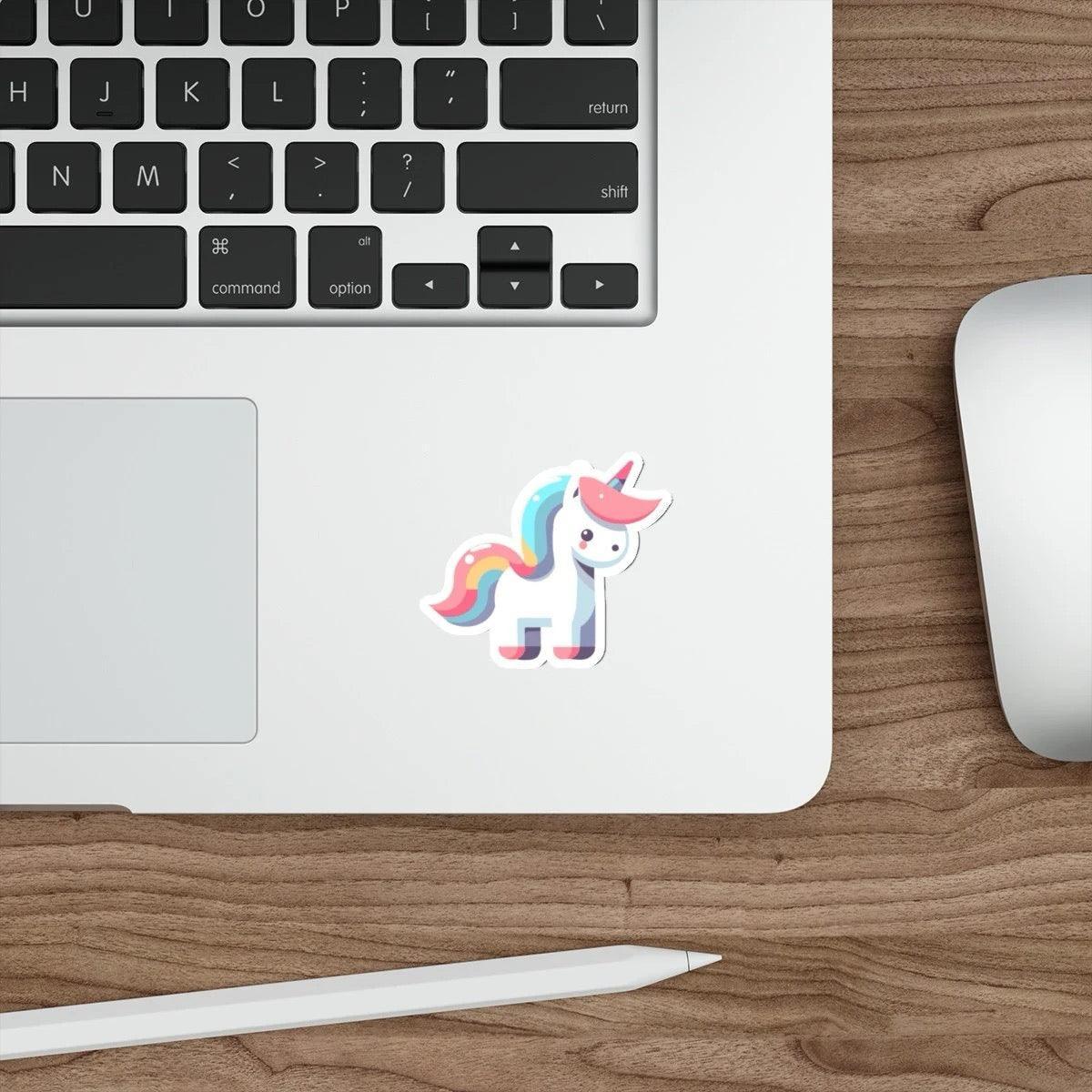 A cartoon unicorn sticker in pastel colors affixed to the side of a laptop, with a keyboard and a mouse in the background on a wooden desk.