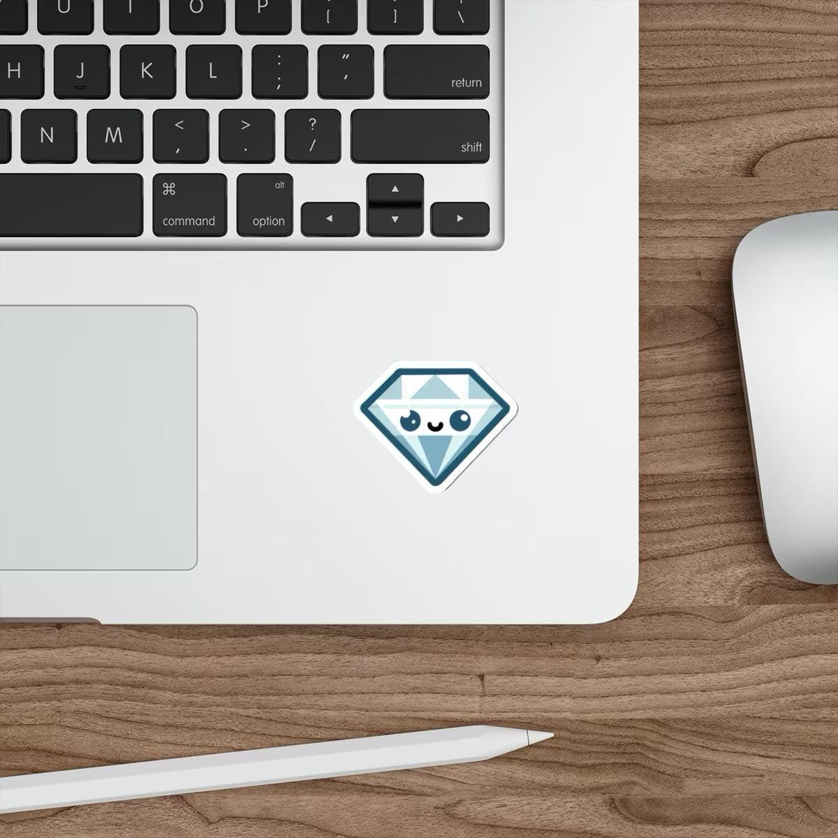 A blue diamond cartoon sticker with a cute face pasted on a laptop next to a computer mouse on a wooden desk.