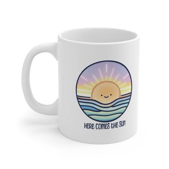 White ceramic mug with a cheerful sun illustration and the positive phrase 'Here Comes the Sun,' ideal for starting the day with a smile