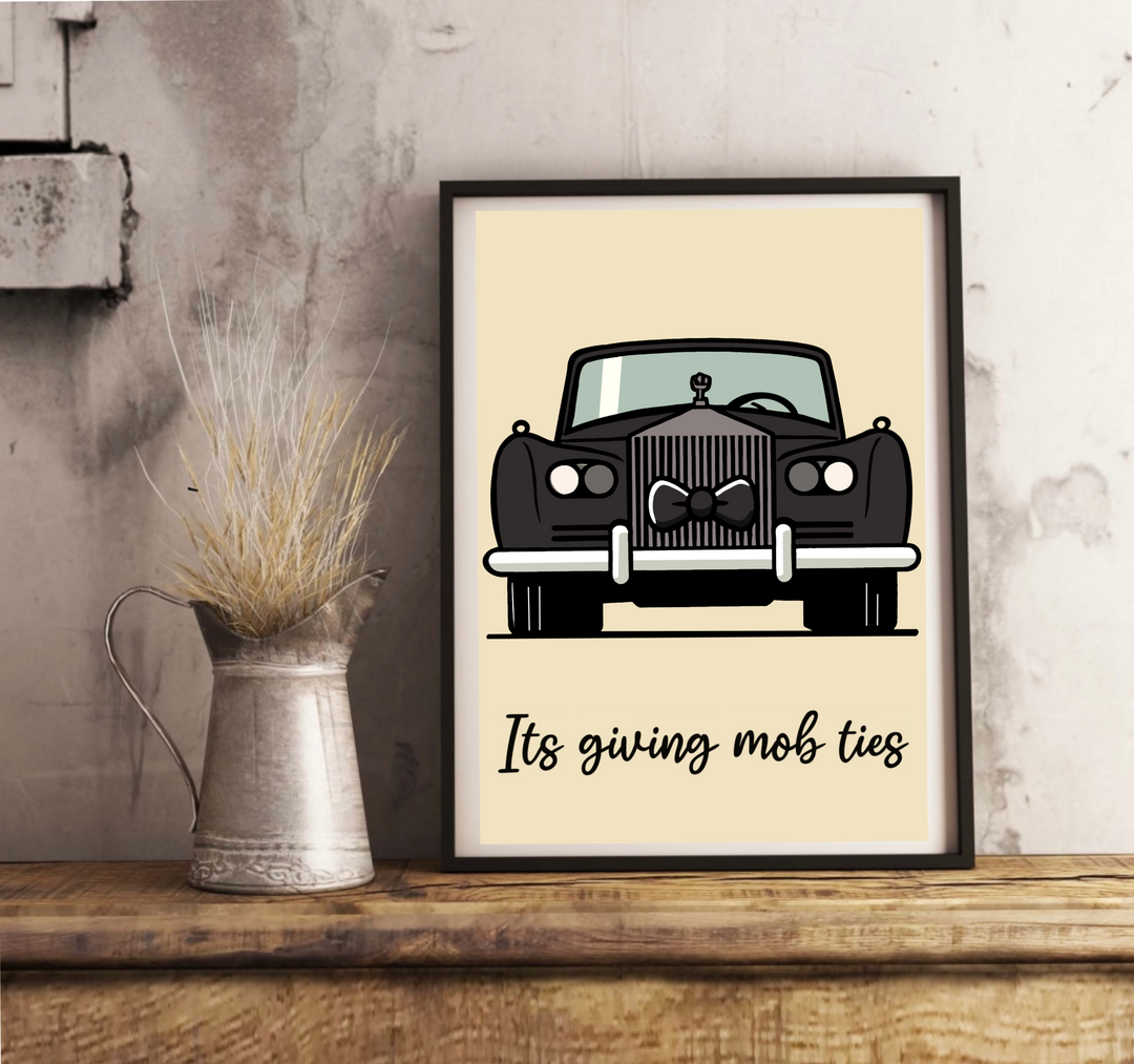 Introducing the charming Mob Ties Print, a delightful piece that's perfect for adding character to your space! This art print rests effortlessly against a crisp white wall, showcased beautifully on a polished wooden floor. Picture an illustrated vintage black car, all dressed up with a snazzy bow tie on its grille, exuding timeless elegance. Below the car, the words "It's giving mob ties" are penned in lovely cursive script, subtly enhancing the light beige backdrop. It's got that classic Rolls Royce vibe w