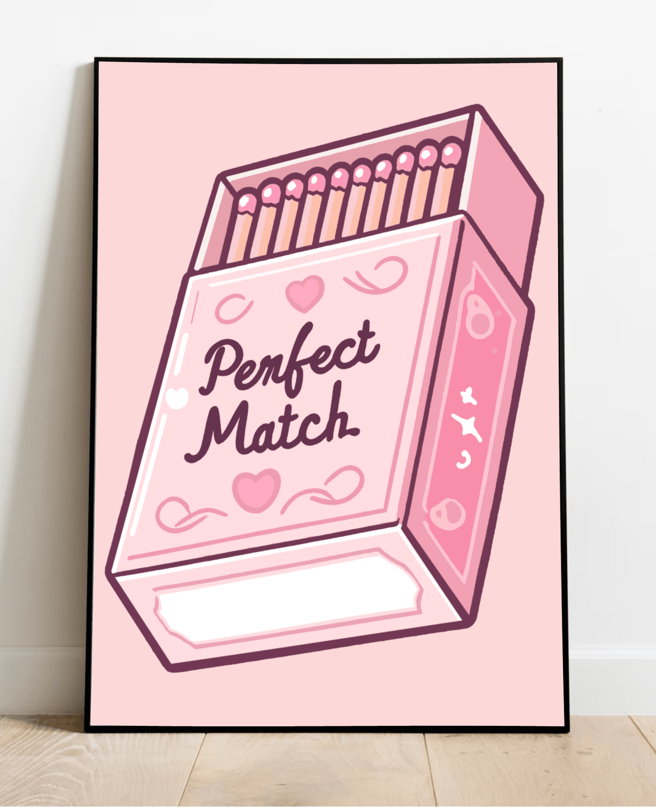 Introducing "The Perfect Match Print"—a charming and whimsically illustrated art piece that's sure to capture hearts! This delightful artwork features a framed pink matchbox set against a soft pink background, adorned with cute hearts, enchanting moons, and twinkling stars. The playful cursive text reads "Perfect Match," adding an extra layer of whimsy. Casually resting on a wooden floor against a pristine white wall, it radiates an aura of lighthearted love that can brighten up any space.