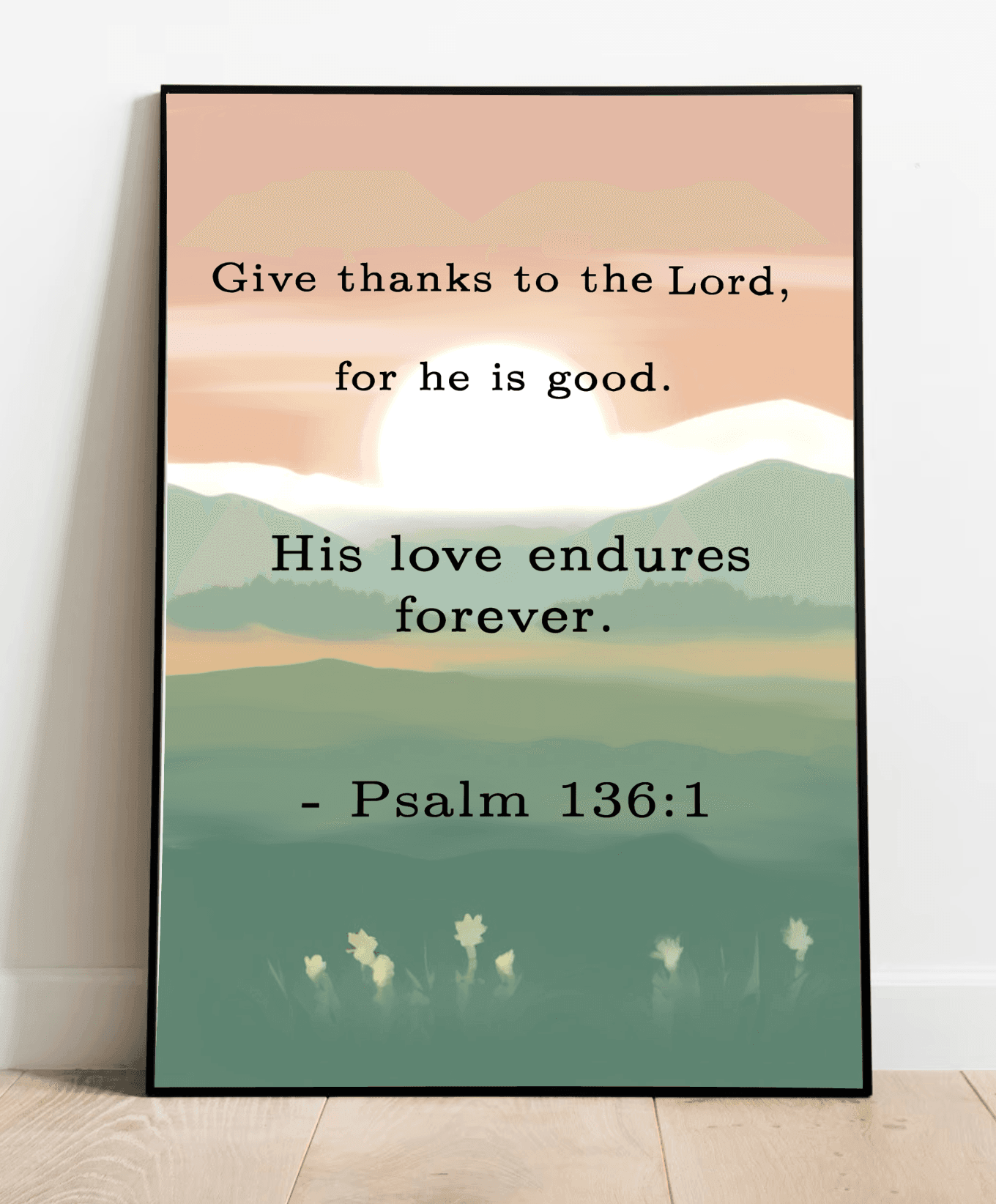 A framed art print with a pastel color background featuring a verse from Psalm 136:1, placed on a wooden floor against a white wall.