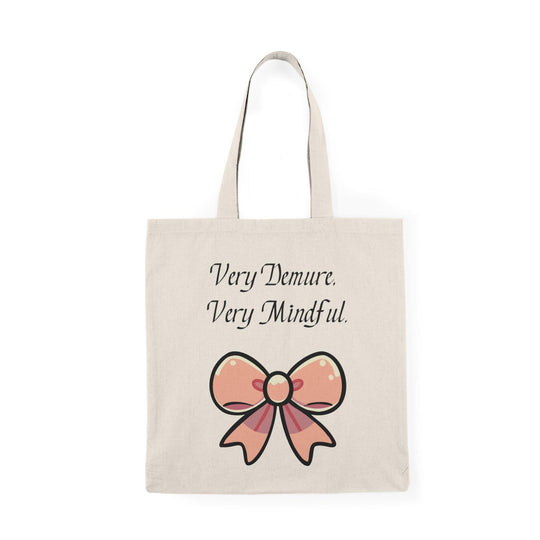 A cream tote bag adorned with a stylish design featuring the phrase 'Very Demure. Very Mindful.' paired with a decorative bow graphic. This elegant design resonates with those who appreciate a sense of calm and mindfulness in their lives