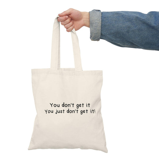 A natural canvas tote bag with a minimalist design featuring the phrase 'You don't get it. You just don't get it!' The straightforward text conveys a sense of frustration in a light-hearted manner, perfect for those who enjoy sarcasm