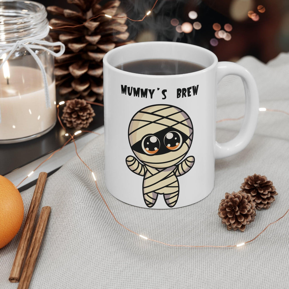 Fun white ceramic mug featuring a cartoon mummy with the playful text 'Mummy’s Brew,' perfect for Halloween or spooky coffee moments.