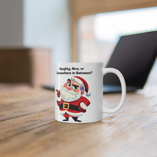 Funny Christmas mug featuring a sassy Santa and the phrase 'Naughty, Nice, or Somewhere in Between?' Perfect for holiday coffee or hot chocolate, this ceramic mug brings humor to festive mornings. Available in 11oz and 15oz sizes
