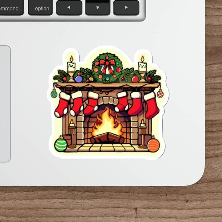Christmas fireplace sticker on a laptop, featuring a decorated holiday fireplace with stockings, wreath, and glowing candles