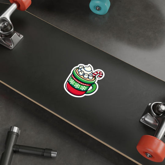 A festive sticker featuring a cozy mug of hot chocolate with whipped cream, marshmallows, and a candy cane, designed in vibrant holiday colors. The sticker is placed on a sleek laptop, showcasing its versatility and cheerful design.