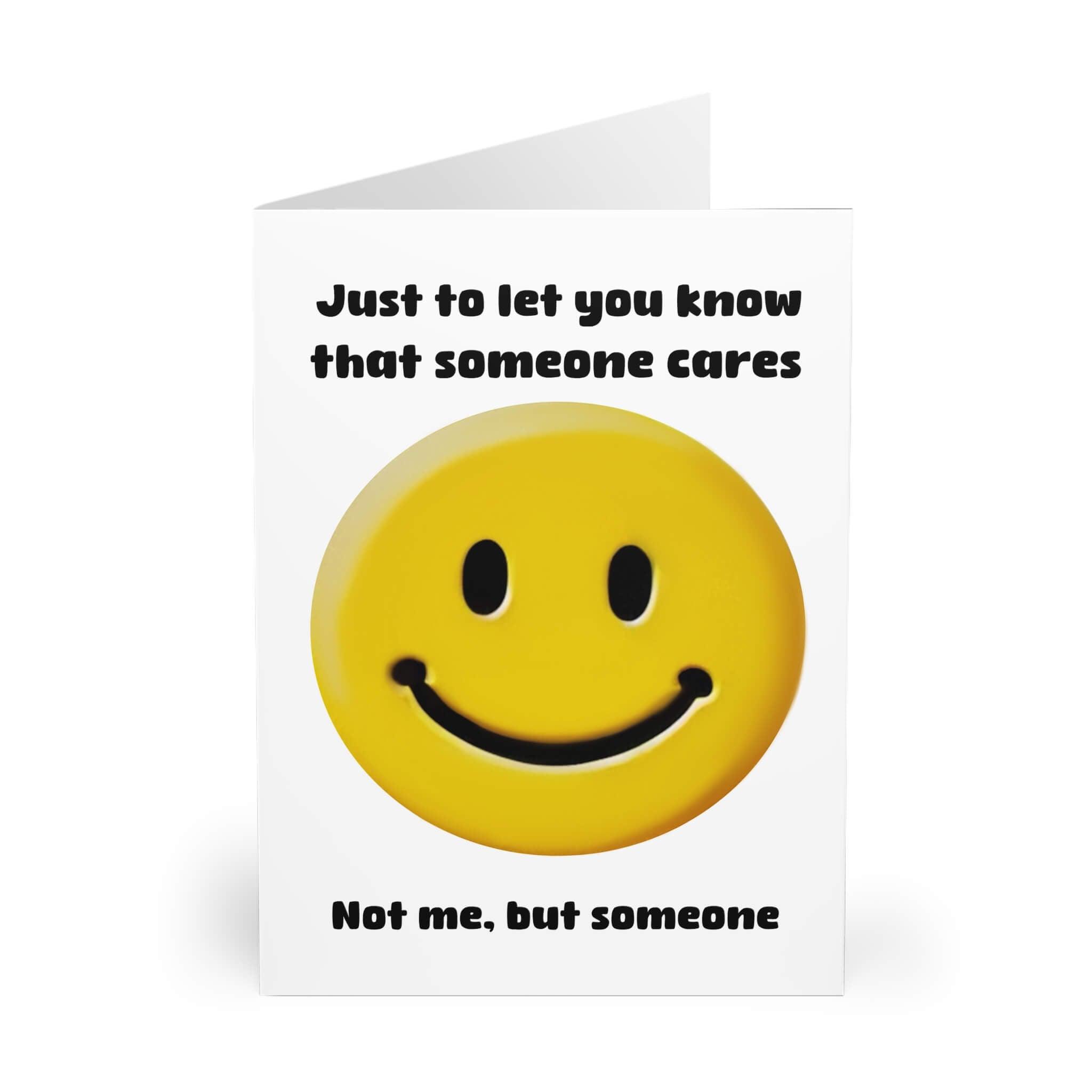 Cheeky greeting card with a bright yellow smiling face emoji and the text 'Just to let you know that someone cares. Not me, but someone' printed in bold black letters